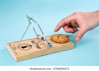 Hand reaching towards a cookie placed on a rat trap in a playful setting