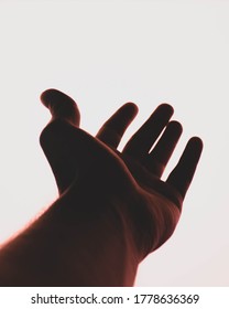 Hand Reaching To White Background Under Red Light.