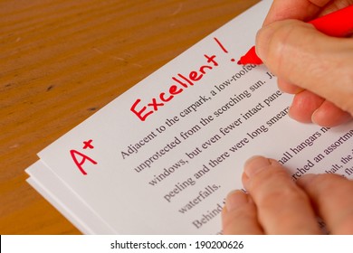 Hand with Red Pen Grading Papers with Excellent - Success concept in education industry  - Powered by Shutterstock