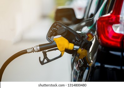 Hand refilling the black car with fuel at the gas station. Oil and gas energy.