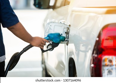 Hand refilling the white pickup truck with fuel at the gas station. Oil and gas energy.