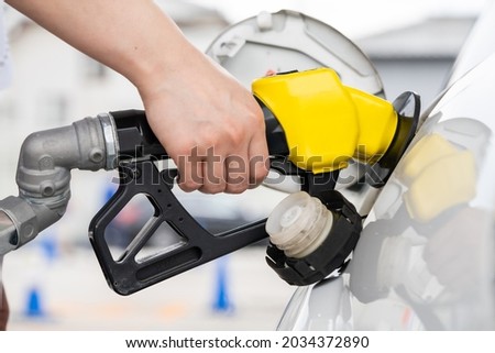 A hand to refuel a car with high-octane gasoline.