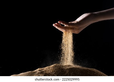 Hand releasing dropping sand. Fine Sand flowing pouring through fingers against black background. Summer beach holiday vacation and time passing concept. Isolated high speed shutter - Shutterstock ID 2225029995