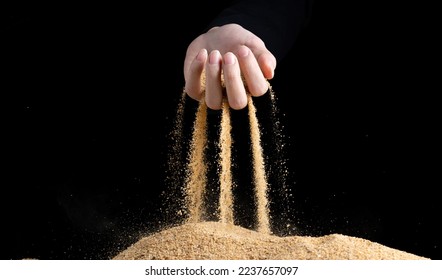 Hand releasing dropping sand. Fine Sand flowing pouring through fingers against black background. Summer beach holiday vacation and time passing concept. Isolated high speed shutter - Shutterstock ID 2237657097