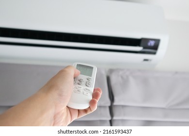 Hand with remote control directed on air conditioner