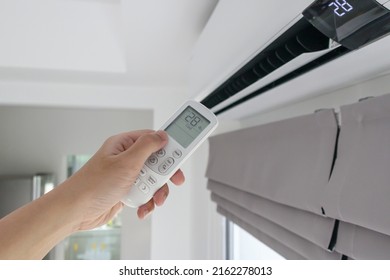 Hand with remote control directed on air conditioner