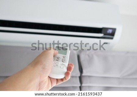 Hand with remote control directed on air conditioner