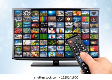 hand with remote on black flat tv screen display with picture movie gallery backdrop. television in front of white blue bokeh background. Computer multimedia streaming internet and cloud concept