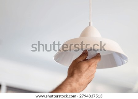 Hand replacing an led light bulb in a white ceiling lamp, home improvement concept