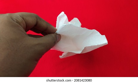 Hand Of Restaurent Cleaner Food Service Industry Employ Taking Coustomers Leftover Used Dirty White Tissue Paper Or Napkin From Red Table Background And Copy Space. Horizontal Close Up Macro Top View.