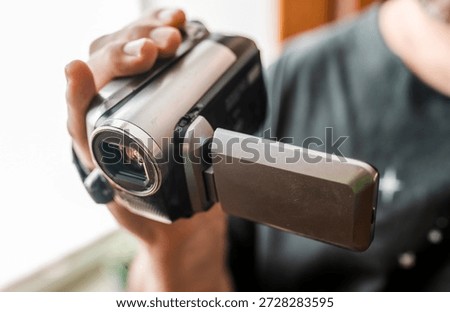 Hand with retro camcoder with LCD flip screen. Y2k technology concept.