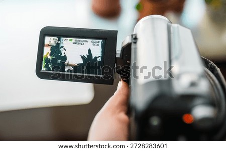 Hand with retro camcoder with LCD flip screen. Y2k technology concept.