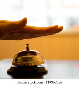 Hand Ringing In Service Bell On Wooden Table.