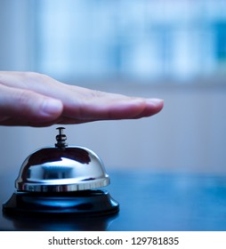 Hand Ringing In Service Bell On Wooden Table.