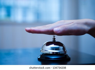 Hand Ringing In Service Bell On Wooden Table.