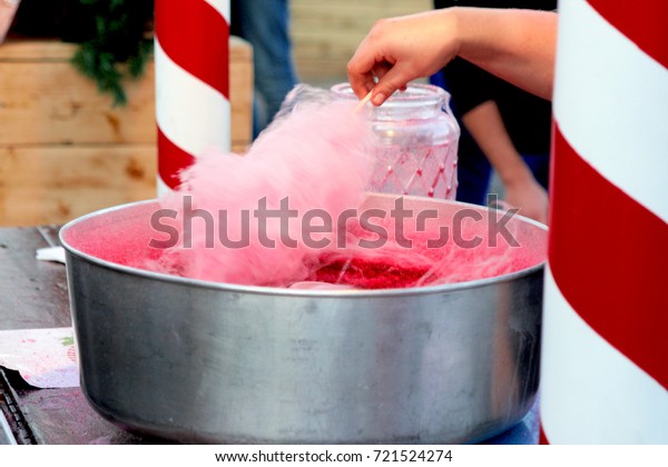 Hand rolling cotton candy in candy floss\
machine. Making candyfloss