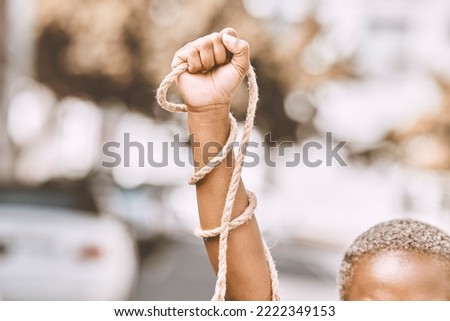 Hand, rope and fist protest slavery for freedom and human rights against an urban background. Activist, activism and rebellion against racism and change for civil, law and government rights