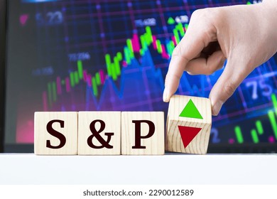 A hand rotates a wooden cube to indicate the fall or rise of S and P