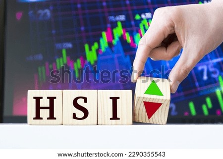 A hand rotates a wooden cube to indicate the fall or rise of the Chinese Stock Index Hang Seng HSI