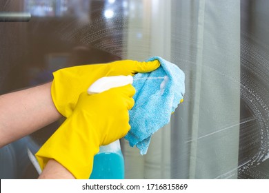 A hand in a rubber glove washes the window in the room