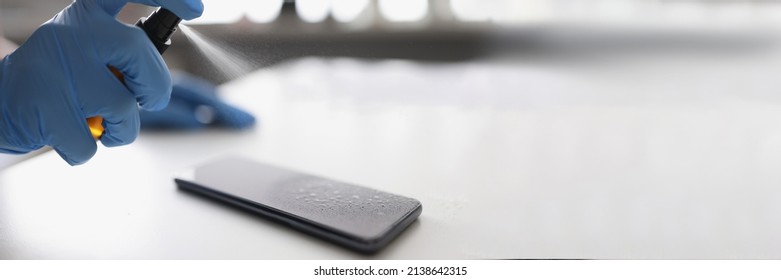 Hand In Rubber Gloves Puffing Antiseptic On Phone Screen Closeup