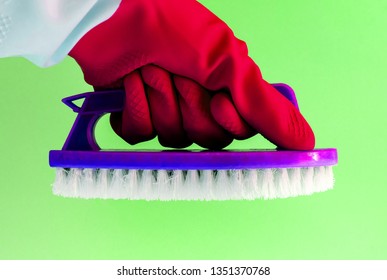 Hand in rubber latex glove with Handheld floor brush cleaning on pink background. cleaning dirt from the premises with a professional commercial cleaning company - Powered by Shutterstock