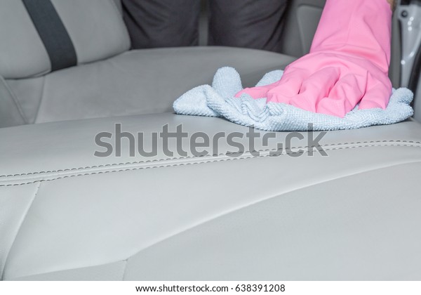 Hand in rubber protective glove with
cloth cleaning a car interior's leather seats. Early spring
professionally chemical cleaning or regular clean
up.