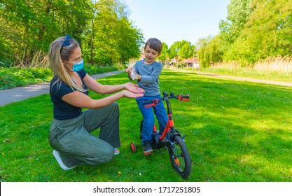 Hand Sanitizer In Public Crowded Place.Mother And Child In The Open Air Wear Facemask During Coronavirus And Flu Outbreak. Virus And Illness Protection