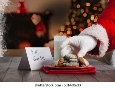 Hand Of Santa Claus Putting Christmas Cookies On Table