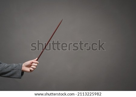 A hand with the school pointer stick shows on the copy space close up. Exam.