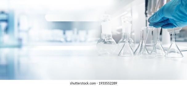 hand of scientist in blue glove with test tube and flask in medical chemistry lab banner background	