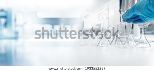 hand of scientist in\
blue glove with test tube and flask in medical chemistry lab banner\
background	