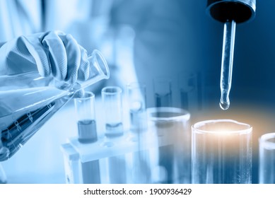 Hand Of Scientist Holding Flask With Lab Glassware In Chemical Laboratory Background, Science Laboratory Research And Development Concept	