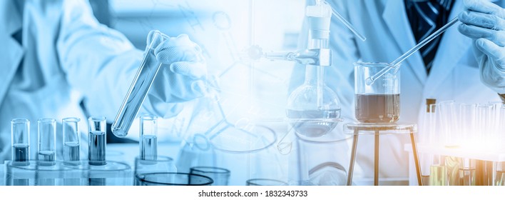 Hand Of Scientist Holding Flask And Pouring Sample To Test Tube In Chemical Laboratory Background, Science Laboratory Research And Development Concept	