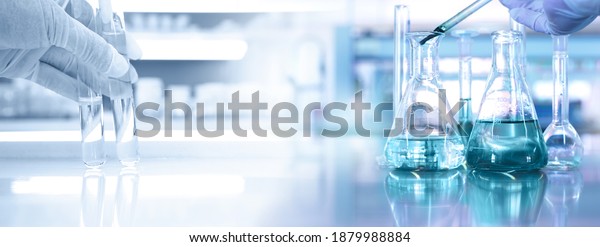 hand of scientist with test tube and\
flask in medical chemistry lab blue banner\
background