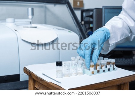 A hand of scientists arrange vials of samples in order before analysis with Fourier Transform Infrared Spectroscopy FTIR instrument. Samples are analysed to identify the chemical identity.