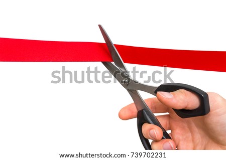 Hand with scissors cutting red ribbon - opening ceremony concept. Isolated on white background