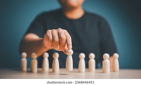 Hand select a wooden human figure from the crown. Team leader choice, choose a new employee from candidates. Business hiring and recruitment. Career opportunity, Leadership, Human Resource Management. - Shutterstock ID 2368446451