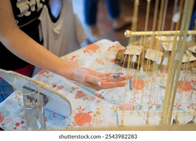 Hand Selecting Necklace at Artisan Jewelry Display - Powered by Shutterstock