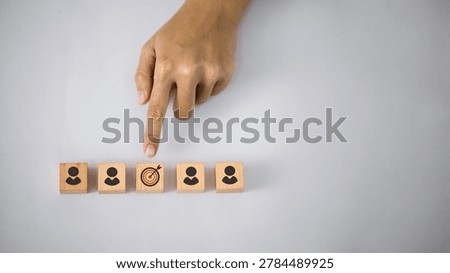 Hand selecting target audience icon among customer symbols, representing customer segmentation, target marketing, recruitment and business strategy concept.