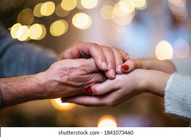 Hand of senior man holding hand of young woman indoors at Christmas, close-up. - Powered by Shutterstock