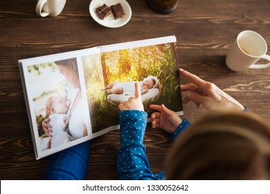 Hand senior woman and child holding a family photo album against the background of the a wooden table.