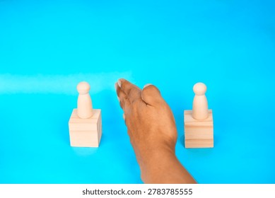 Hand separating two figures on blocks, representing conflict mediation, boundaries, negotiation, and relationship management.
