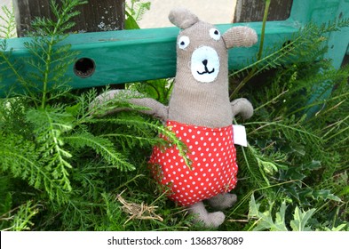 Hand sewn, hand made cute and funny teddy bear wearing dotted red pants in a summer garden