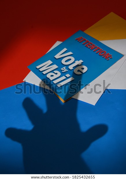 A\
hand shadow is stealing a vote by mail envelope for a symbolic\
message about voter fraud in the upcoming\
election.