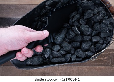 A hand with a shovel digging out anthracite nut coal from a coal scuttle - Shutterstock ID 1919003441