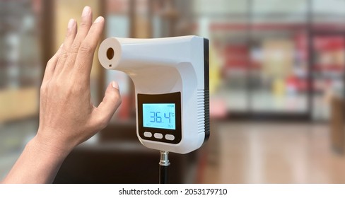 Hand show up of The entrance door with Digital thermometer temperature scanning machine before walk in the store in situations disease COVID-19 virus. - Shutterstock ID 2053179710