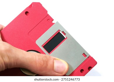 Hand showcasing a red floppy disk magnetic surface, closeup of vintage data storage media and retro technology, old school file backup concept, obsolete magnetic diskette