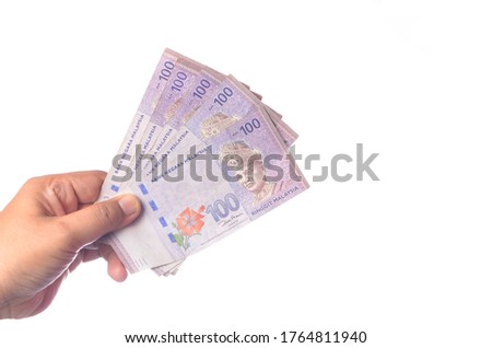 Hand showing 100 Ringgit Malaysia (MYR) money with over white  background and selective focus.
