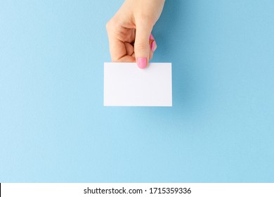 Woman’s Hand Showing Blank Business Card On Blue Background. Mockup